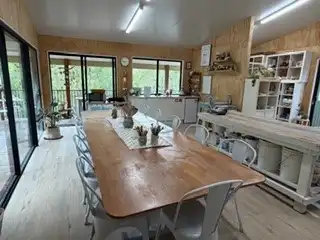 The studio’s long timber table set for a class, with big windows onto the bush